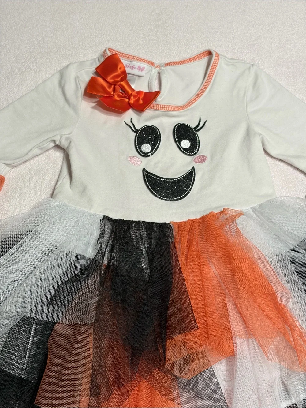 Cutie Halloween costume Has orange, black, and white tulle skirt and wrists.